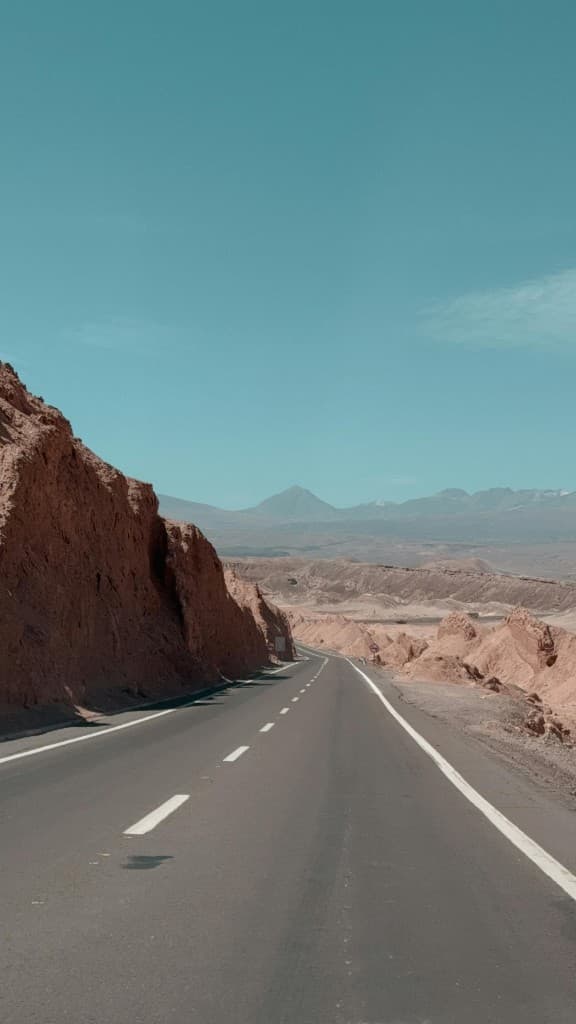 Vast Atacama desert landscape with road toward distant volcanoes