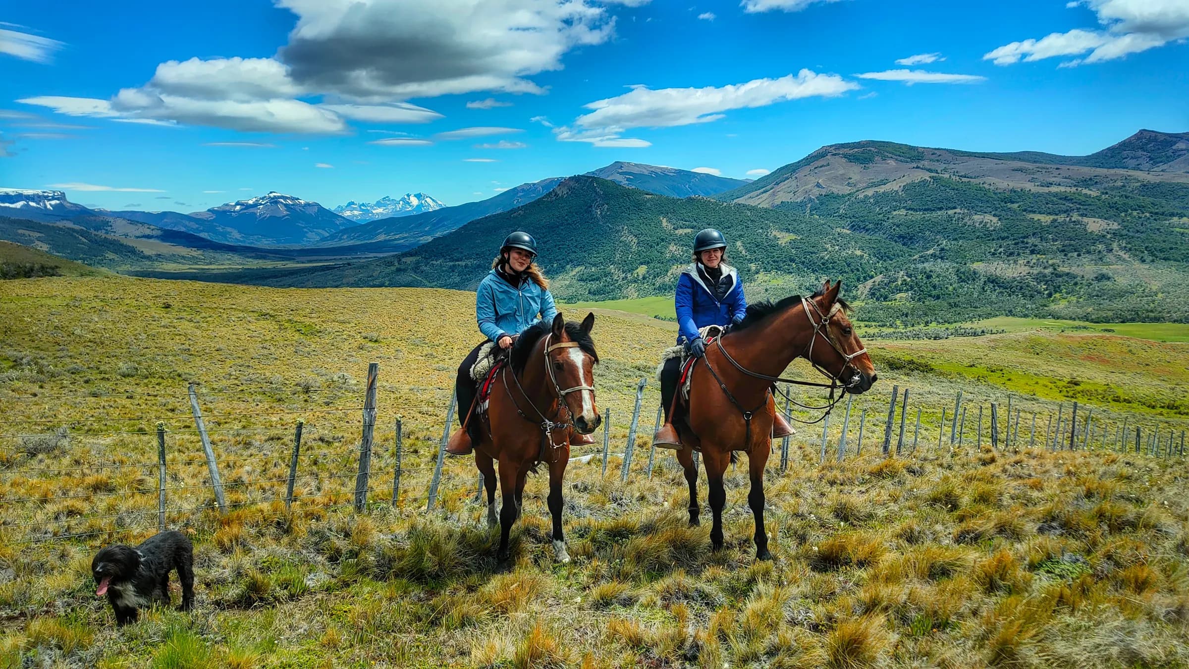 Two riders on horseback crossing a green valley, Patagonia