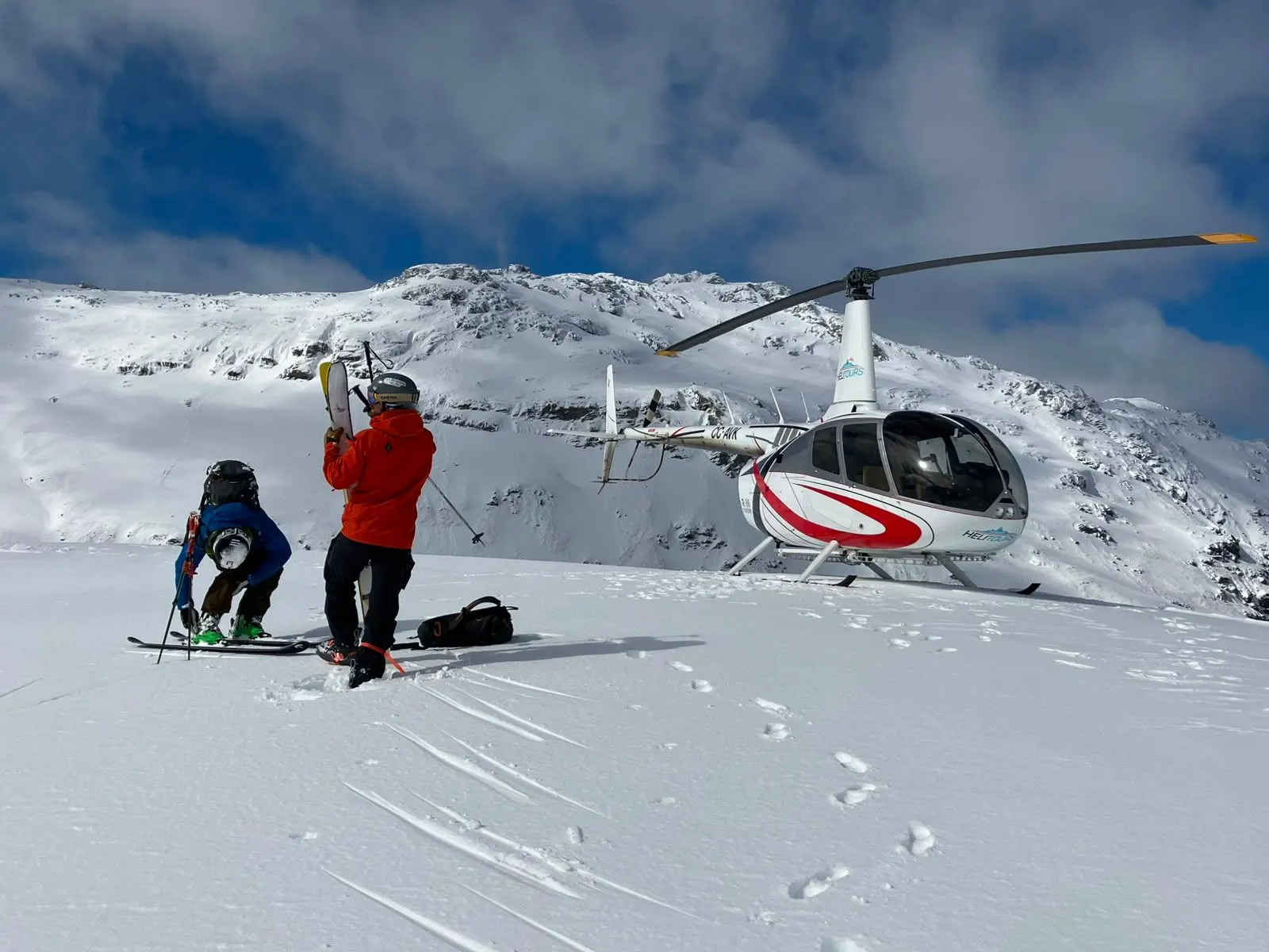 Helicopter landed on a snowy ridge with skiers, Central Andes